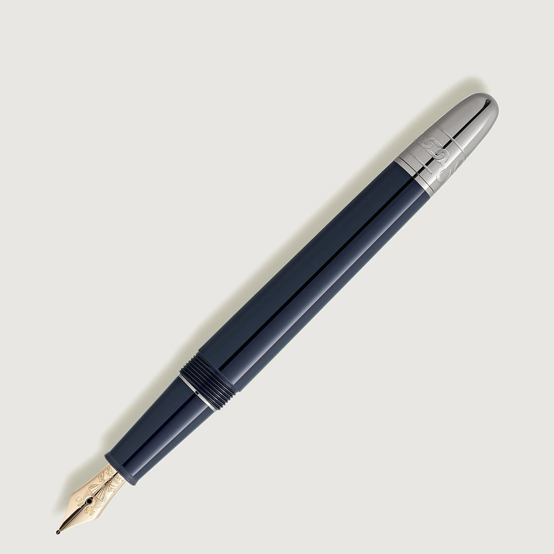 A sleek Montblanc Meisterstück Around the World in 80 Days Classique fountain pen in navy blue with a silver nib and cap top. It features a glossy, smooth finish and slightly rounded body, positioned diagonally on a light gray background.