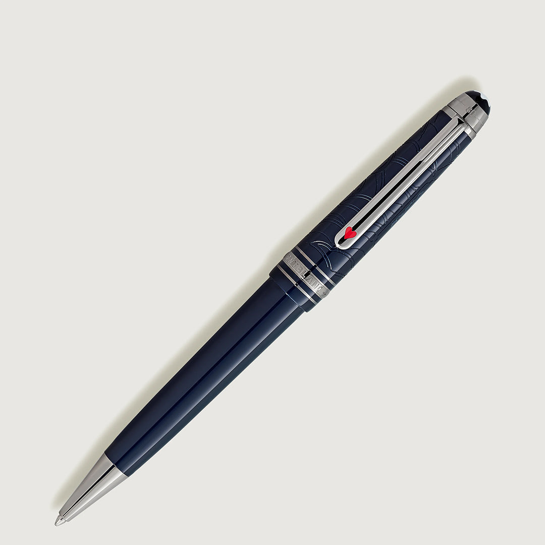 The Montblanc Meisterstuck Around the World in 80 Days Classique Ballpoint Pen features a sleek navy design with silver accents inspired by a Jules Verne adventure. It has an engraved barrel and a clip adorned with a red emblem against a light gray background.