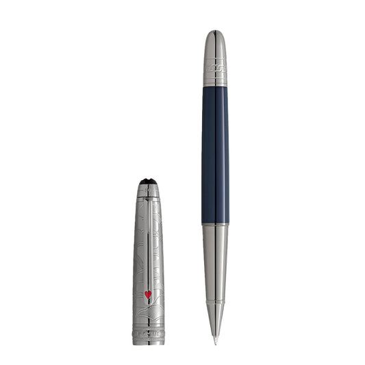 The Montblanc Meisterstück Around the World in 80 Days Doué Classique Rollerball Pen features a sleek silver and blue design with an intricate cap, including a small red heart. Inspired by Jules Verne, it embodies adventure and stands upright gracefully with its cap beside it.
