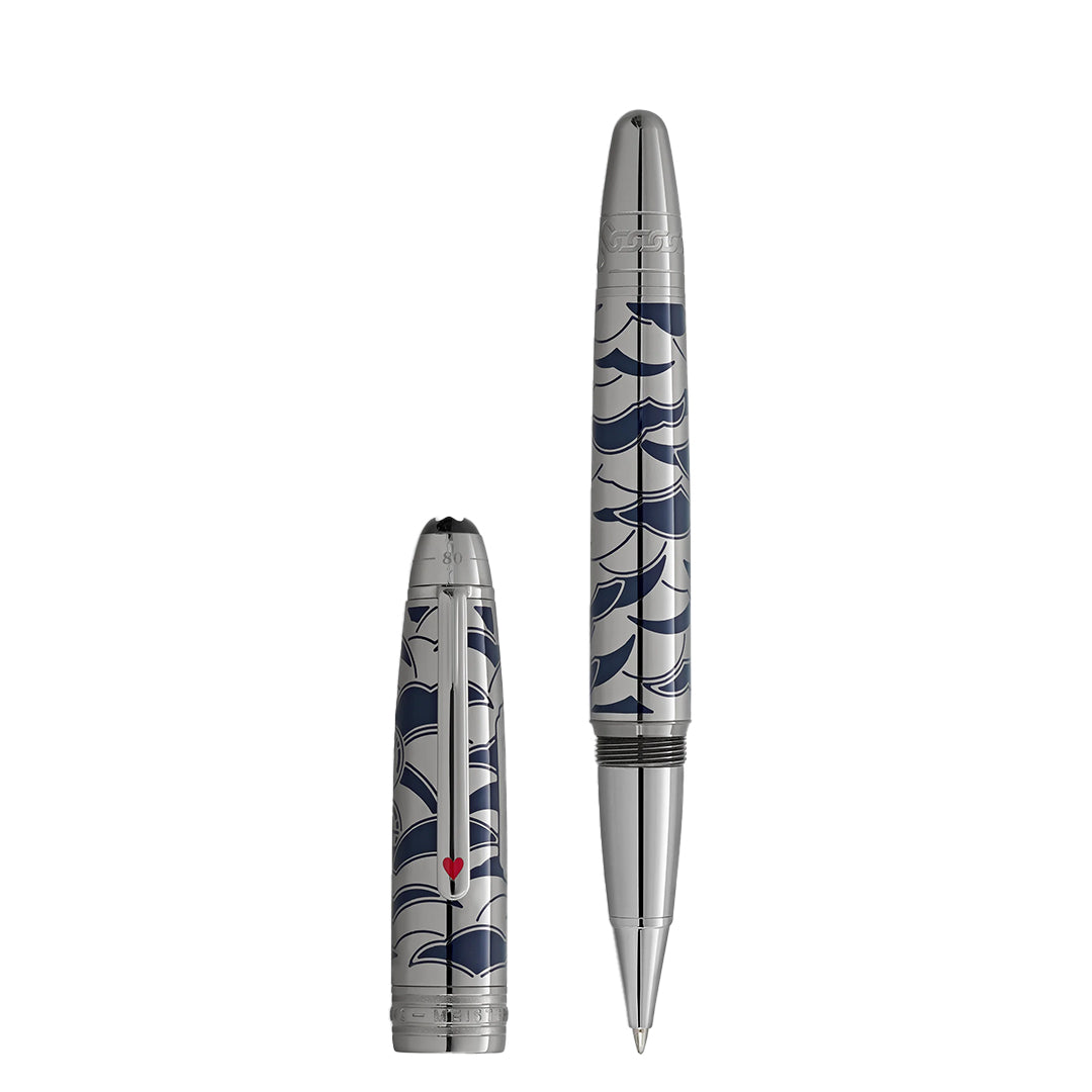 The Montblanc Meisterstück Around the World in 80 Days Solitaire LeGrand Rollerball Pen and its cap, both featuring a blue wave pattern with a small red heart, stand upright on a white background.