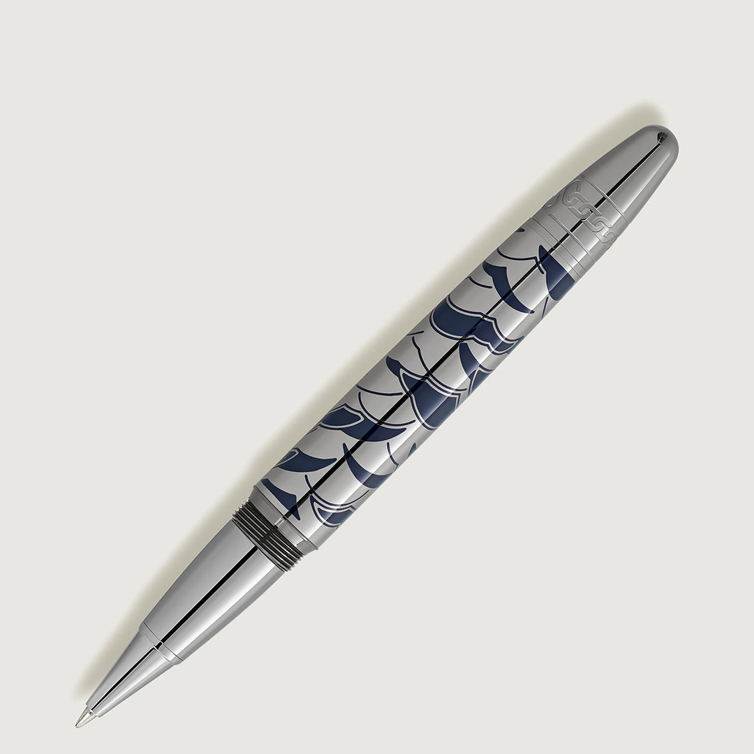 A Montblanc Meisterstück Around the World in 80 Days Solitaire LeGrand Rollerball Pen with a glossy silver finish and dark blue abstract wave pattern inspired by Jules Verne rests diagonally on a plain light background.