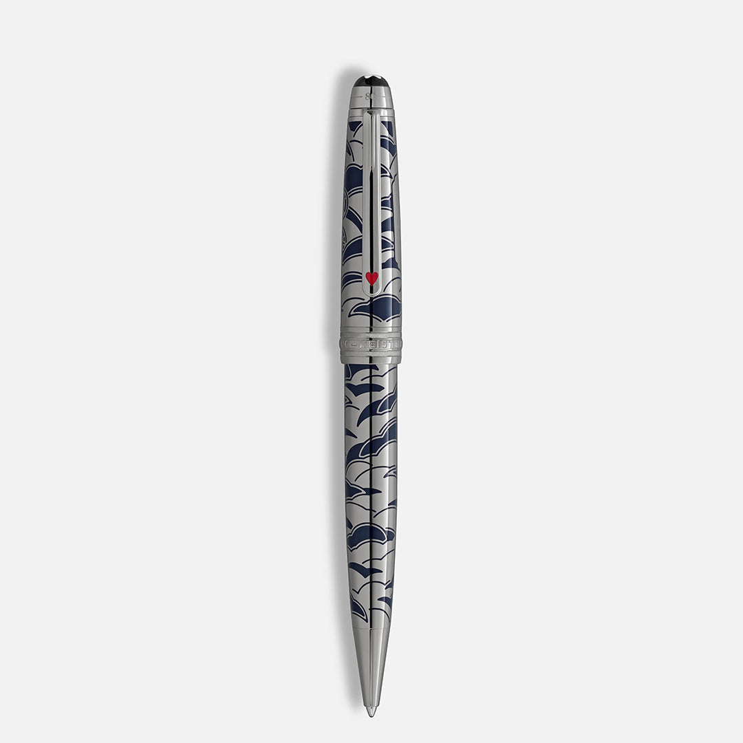 A Montblanc Meisterstück Around the World in 80 Days Solitaire Midsize Ballpoint Pen with a blue geometric wave pattern and small red heart detail stands vertically against a plain, light background.