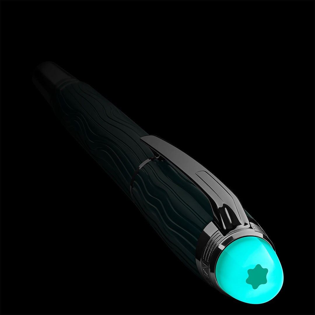 A close-up of the Montblanc Starwalker Polar Green Precious Resin Fineliner Pen showcases its wavy textured barrel and glowing turquoise cap with a star emblem, highlighted against a black background.