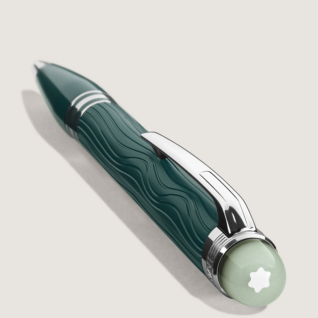 The Montblanc Starwalker Polar Green Precious Resin Ballpoint Pen, featuring silver accents, a wavy textured barrel, and a light green cap with a white star emblem, rests on a light surface with a soft shadow.