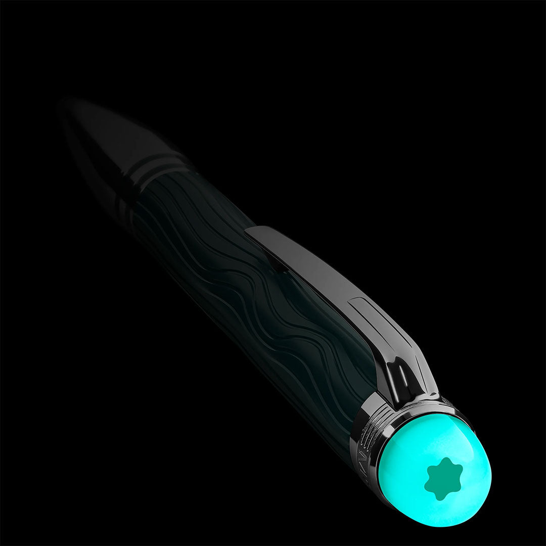 A close-up of the Montblanc Starwalker Polar Green Precious Resin Doue Ballpoint Pen showcases its wavy textured grip and glowing turquoise cap with a star-shaped logo, set against a black background.