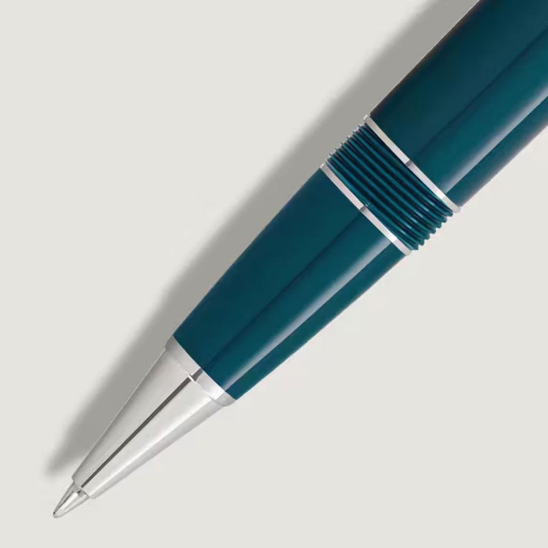 A close-up of the Montblanc Meisterstuck Romeo & Juliet Midsize Ballpoint Pen, featuring blue and teal resin with silver accents, shown diagonally on a light gray background, highlights the pen tip and barrel.
