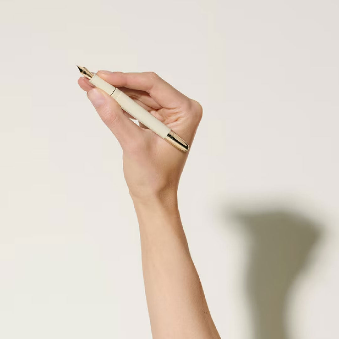 A hand holds the Montblanc Meisterstuck Romeo & Juliet Classique Fountain Pen upright against a plain light background, with both the pen and the hand’s shadow visible.