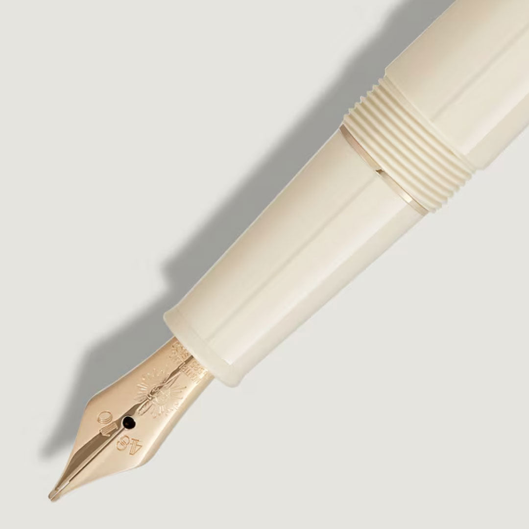 Close-up of the Montblanc Meisterstück Romeo & Juliet Classique Fountain Pen by Montblanc, crafted in cream-colored precious resin with a gold nib featuring decorative engravings, set against a light background.