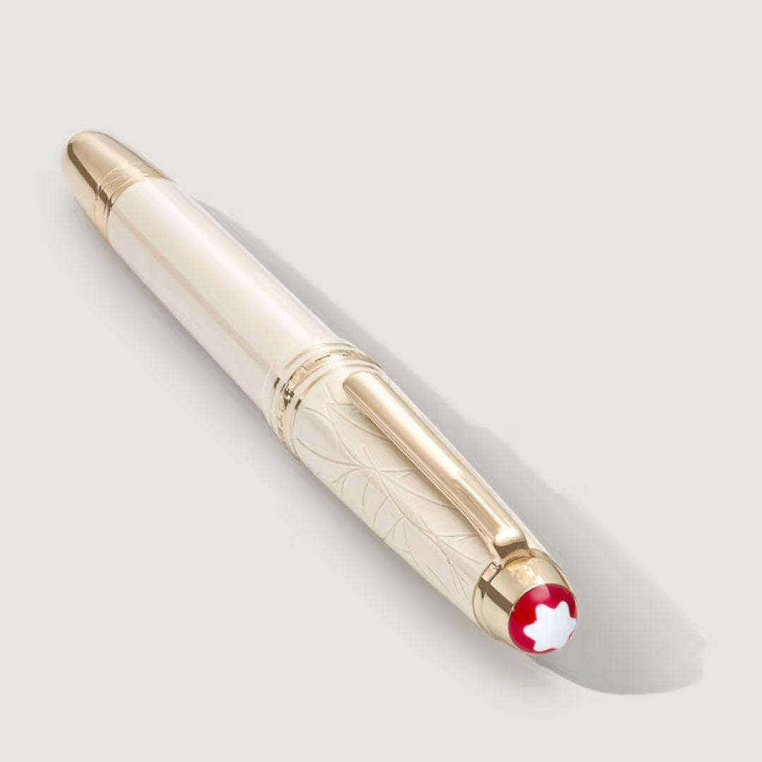 A Montblanc Meisterstück Romeo & Juliet Classique Fountain Pen in white and gold resin, with intricate engraving and a red-and-white emblem on the cap, rests on a light gray surface casting a soft shadow.
