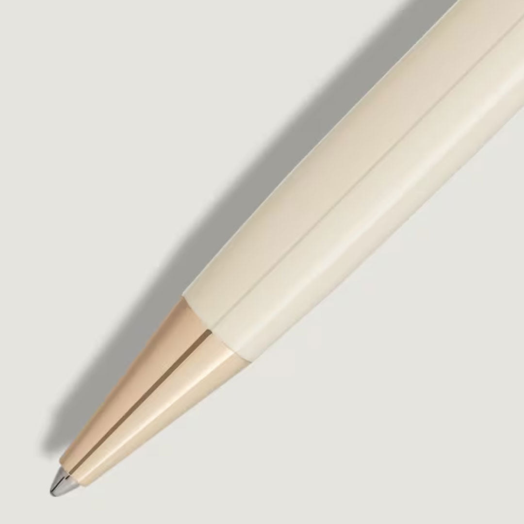 A close-up of the Montblanc Meisterstuck Romeo & Juliet Classique Ballpoint Pen, crafted from ivory-toned precious resin, rests on a light grey surface with its tip and body casting a gentle shadow to the left.