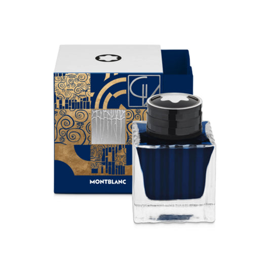 A Montblanc Masters of Art Homage to Gustav Klimt Blue 50ml ink bottle is showcased in front of its decorative box. The square bottle, topped with a black cap and displaying the Montblanc star emblem, holds the blue ink dedicated to Gustav Klimt. Its box is adorned with intricate gold and blue designs, reflecting the craftsmanship of the Masters of Art collection.