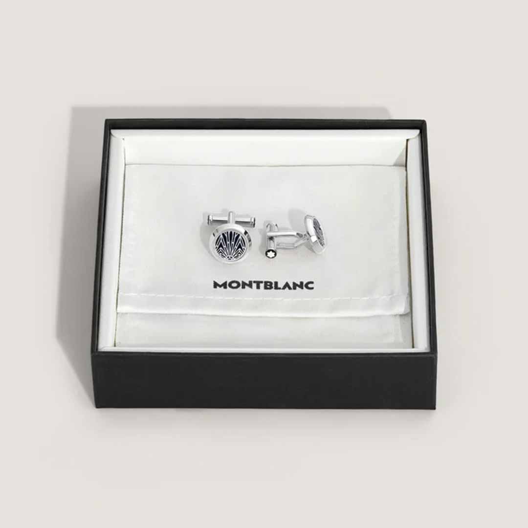 A pair of Montblanc Meisterstück The Origin Collection Blue Cufflinks is elegantly displayed in an open black box with a white interior. Featuring a circular pattern design, these cufflinks rest on a Montblanc-branded cloth inside the box, showcasing their exquisite craftsmanship in stainless steel.
