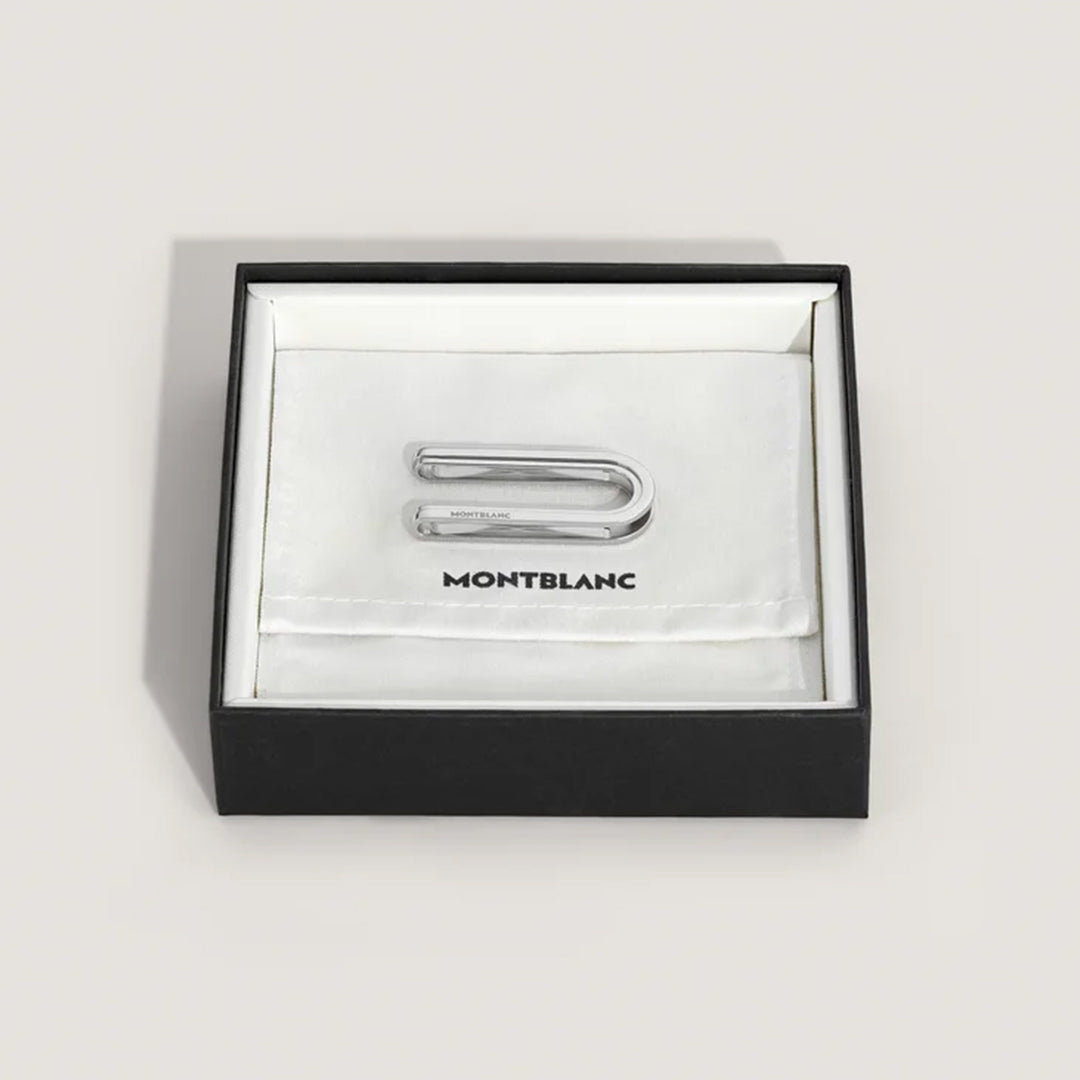 The Montblanc Great Characters Homage To The Great Gatsby stainless steel money clip, evoking the elegance of The Great Gatsby, is displayed in an open black box with a white interior. The silver piece rests on a white cloth branded with "Montblanc.