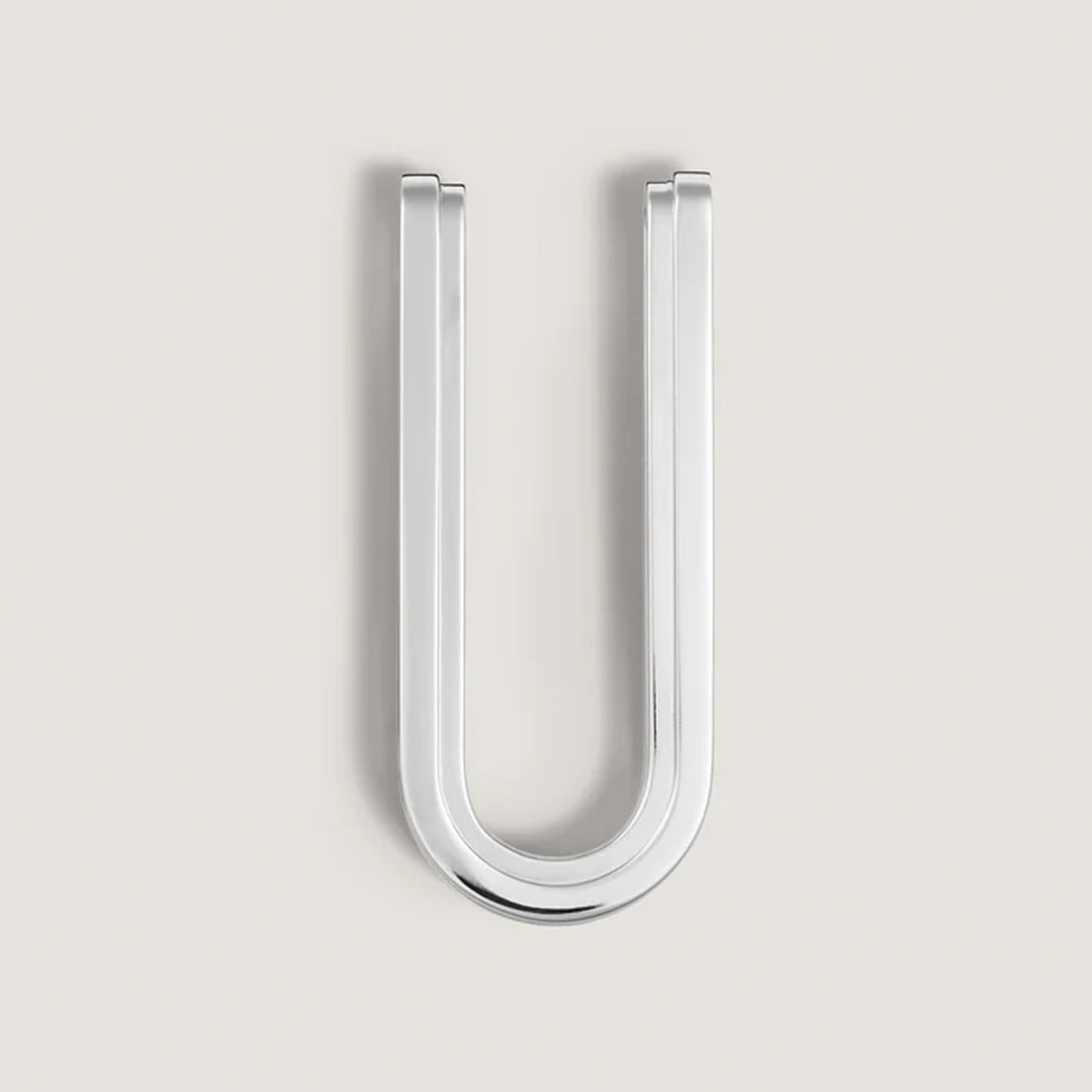 On a light gray background, the Montblanc Great Characters Homage To The Great Gatsby stainless steel money clip is centered. Its elongated, upside-down U shape with smooth rounded edges and polished finish evokes the opulence of The Great Gatsby.