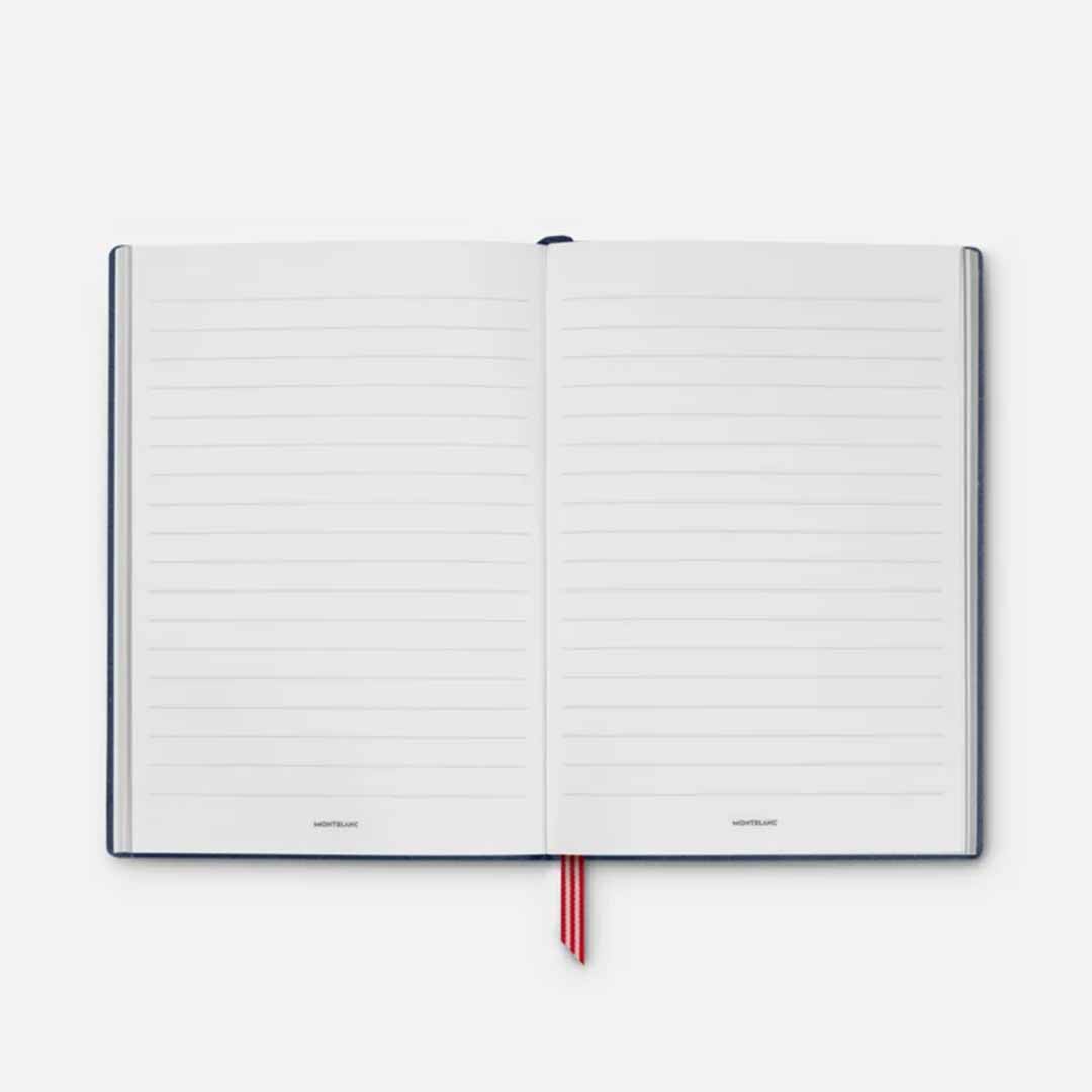 A Montblanc Great Characters Homage to the Great Gatsby #146 Blue Lined Notebook is open and lies flat, featuring lined pages and a red ribbon bookmark prominently placed in the center. As part of the Great Gatsby collection, it presents a dark, luxurious cover set against a neutral light background.