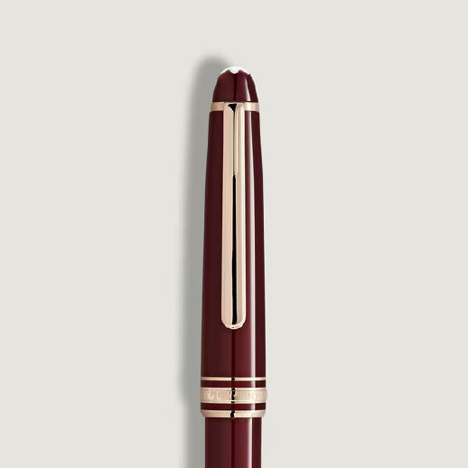 A Montblanc Meisterstuck Burgundy Red Classique Ballpoint Pen with gold accents and clip, shown vertically against a light gray background.