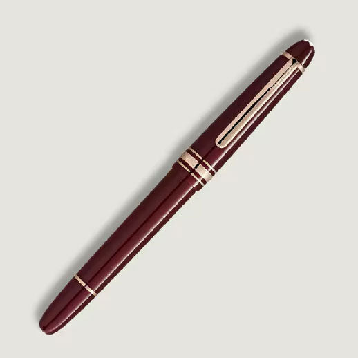 A Montblanc Meisterstuck Burgundy Red Classique Fountain Pen with gold accents and a clip is positioned diagonally on a light gray background.