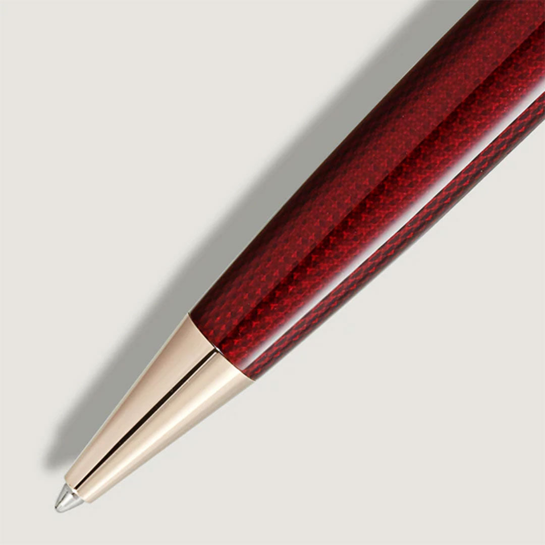 A close-up of a Montblanc Meisterstück Solitaire Golden Hour Ballpoint Pen in burgundy red lacquer with gold-coated accents and a silver tip, shown diagonally on a light grey background.