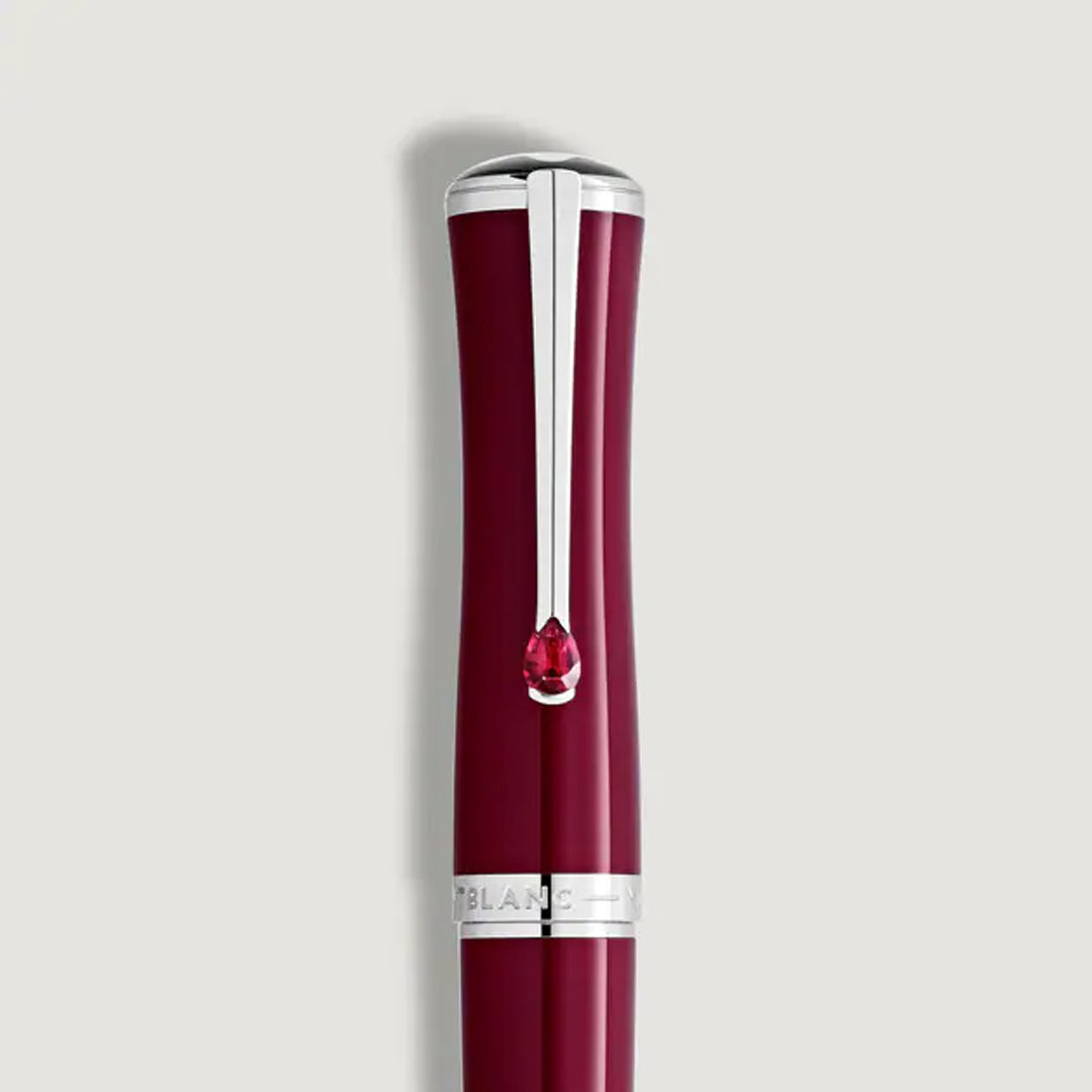 A close-up of a Montblanc Maria Callas Special Edition Rollerball Pen with a silver clip and red gem detail near the top, set against a plain light gray background.