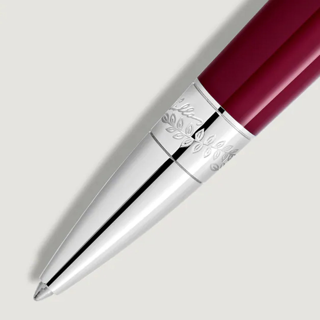 A close-up of the Montblanc Maria Callas Special Edition Ballpoint Pen showcases its ruby color, shiny silver tip, and engraved leaf pattern on the silver band, positioned against a light gray background.