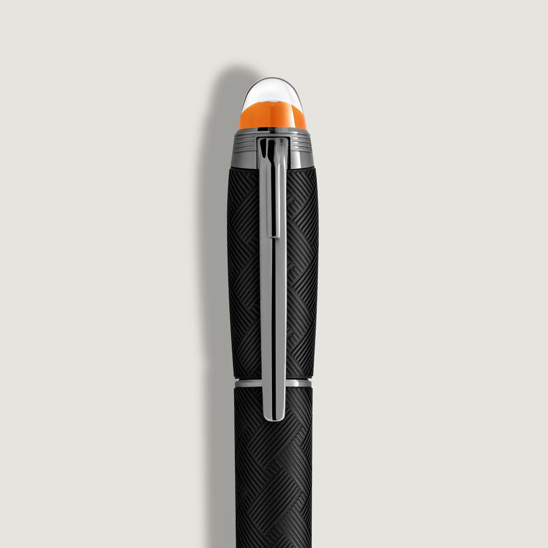 A close-up of the Montblanc StarWalker Extreme Precious Resin Fineliner Pen, featuring a textured geometric barrel, ruthenium-coated accents, and a translucent cap with orange and white details, set against a light gray background.