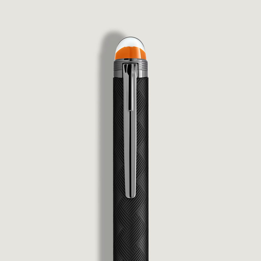 A close-up of the black patterned barrel and silver clip of the Montblanc StarWalker Extreme Precious Resin Ballpoint Pen, featuring ruthenium-coated fittings and an orange-white domed top, set against a plain light background.