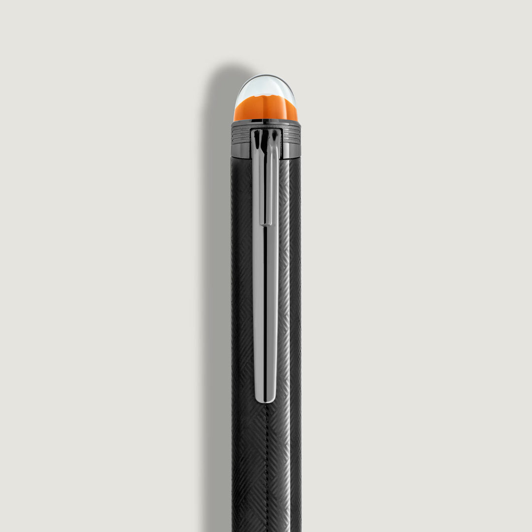 A close-up of the Montblanc StarWalker Extreme Metal Ballpoint Pen shows its textured black body, ruthenium-coated fittings, silver clip, and rounded cap with signature orange and white accents against a light background.