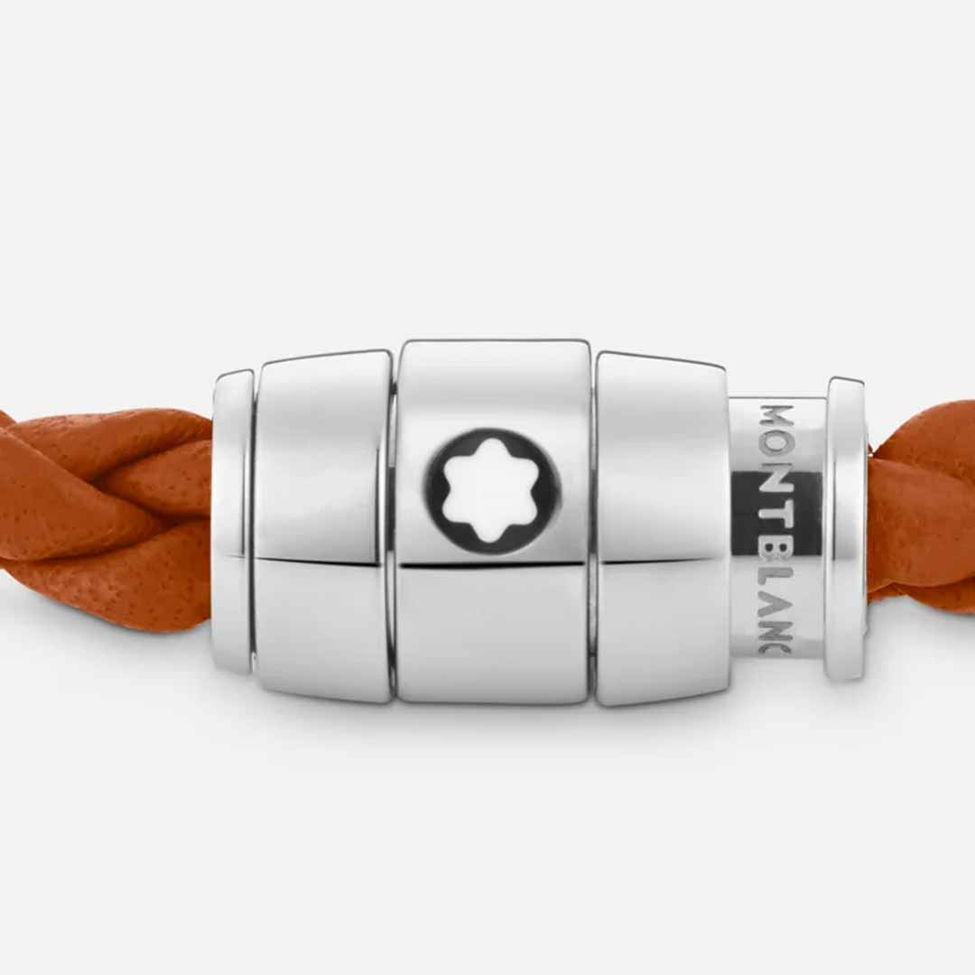 A close-up of the Montblanc Meisterstuck Collection Steel 3-Ring Rust Leather Bracelet reveals a stainless steel clasp. The sophisticated Montblanc emblem adorns the silver fastening, effortlessly joining the braided rust leather bands.