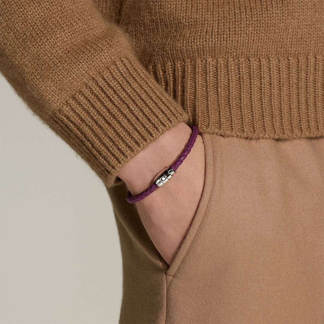 A person in a tan sweater and pants has their hand in their pocket, revealing a Montblanc Meisterstück 3 Rings Cassis Leather Bracelet on their wrist.