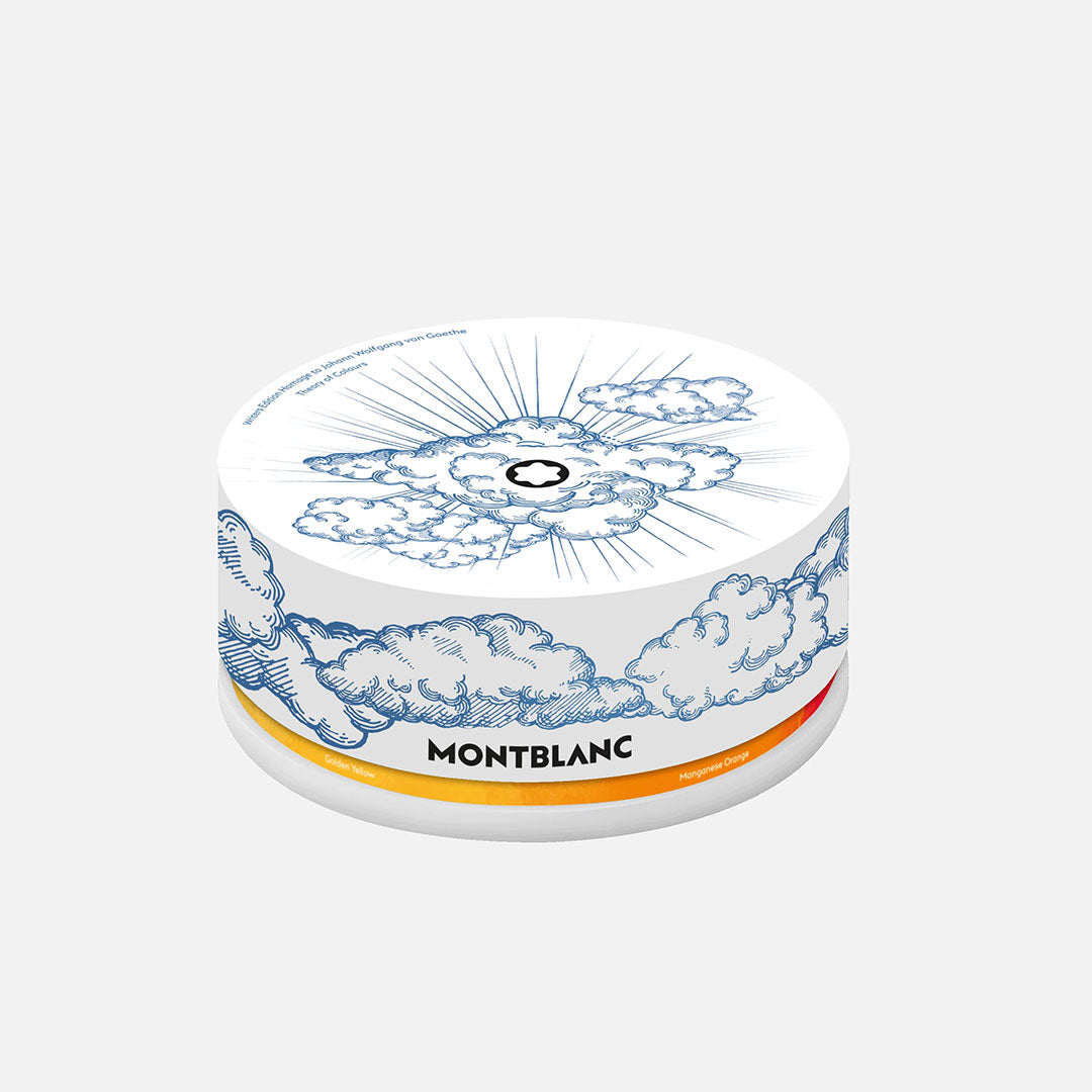 A round white tin from Montblanc, featuring blue clouds, rays, and the brand logo. Inspired by the Writers Edition Homage to Johann Wolfgang von Goethe 6x30ml Ink Bottles Set, it includes a gradient orange-yellow stripe and "Montblanc" on the side.