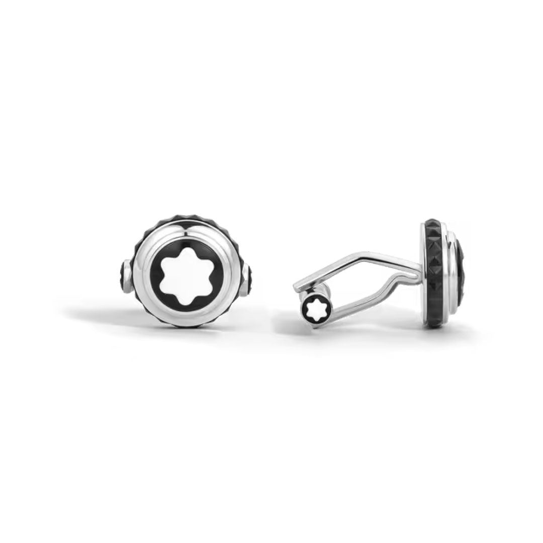 A pair of Montblanc Great Characters Homage to Queen Cufflinks, round and steel, feature a black and white star emblem at the center. Shown on a white background, one cufflink stands upright while the other lies on its side.