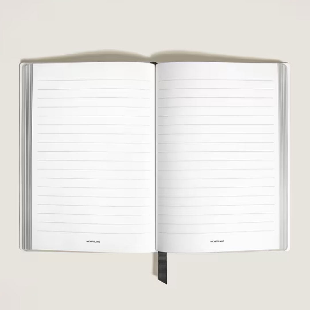 An open Montblanc Great Characters Homage to Queen Medium Notebook lies on a light surface, displaying its blank lined pages and a black ribbon bookmark at the bottom center.
