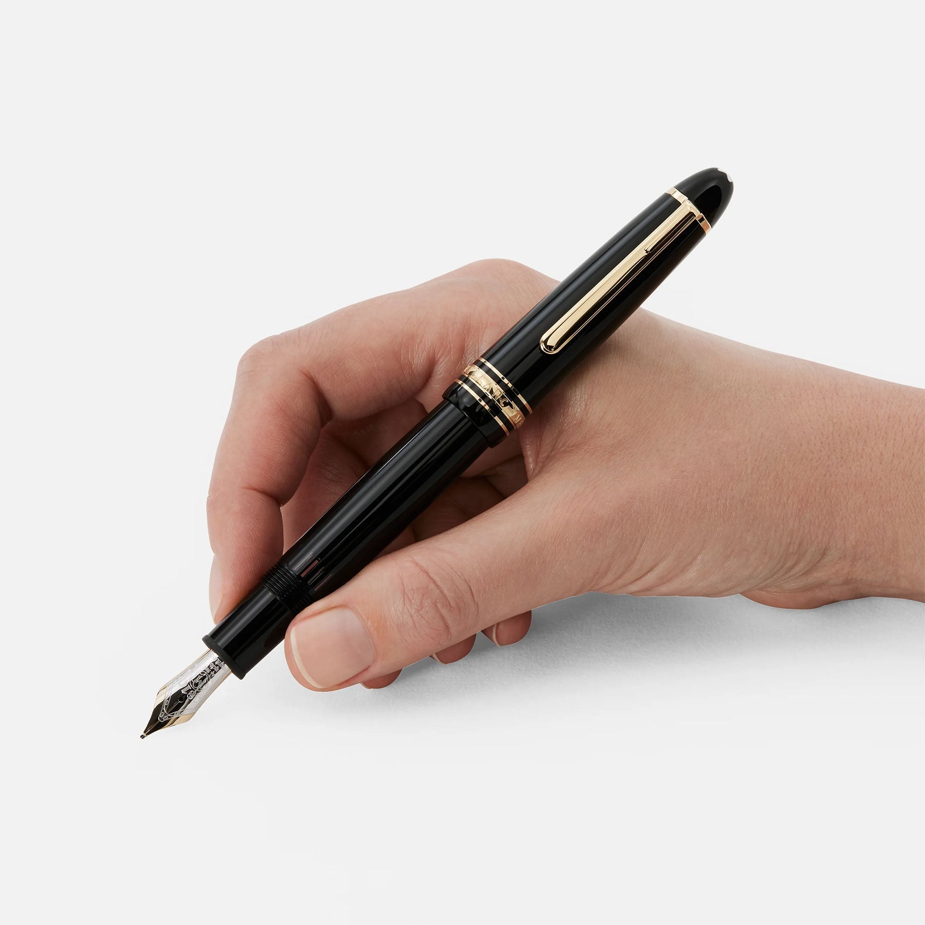 A hand holding the Montblanc Meisterstuck Gold-Coated Le Grand Fountain Pen. This elegant instrument, adorned with luxurious gold accents and a shining nib, is poised to write against a plain white background.