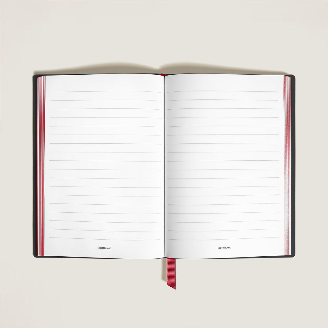 A Montblanc Writers Edition Homage to Bram Stoker Medium Leather Notebook with lined pages, a black cover, and red ribbon bookmark lies open on a light-colored surface.
