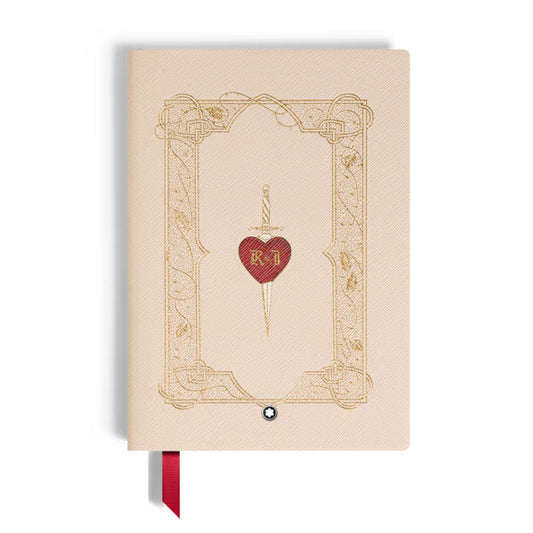 The Montblanc Meisterstuck Romeo & Juliet Medium Notebook features a beige cover with a gold-embossed ornate border, a red heart pierced by a gold sword and "R I" initials at the center, plus an elegant red ribbon bookmark.