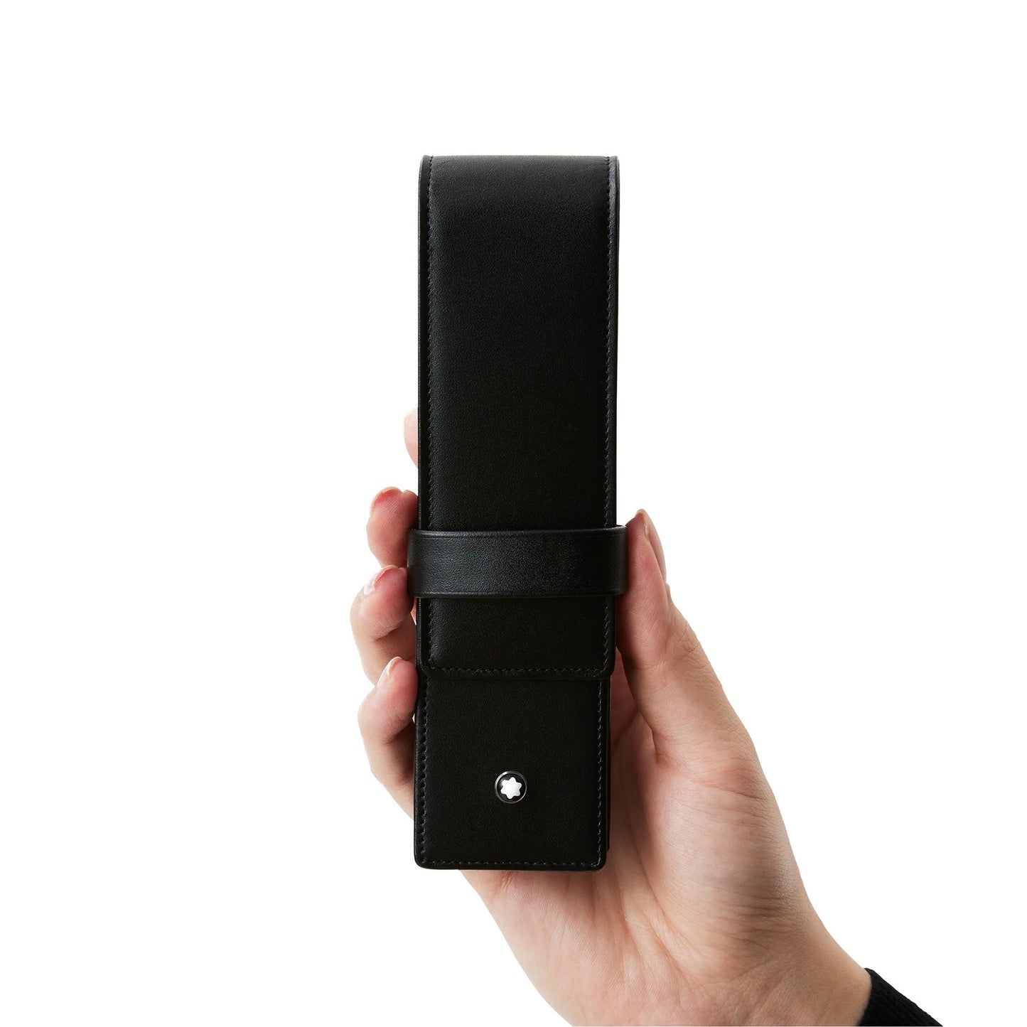 A hand grasps the Montblanc Meisterstück Black Leather Pen Pouch, featuring a sleek design with a flap closure and a small, circular metallic emblem near the bottom, set against a plain white background.