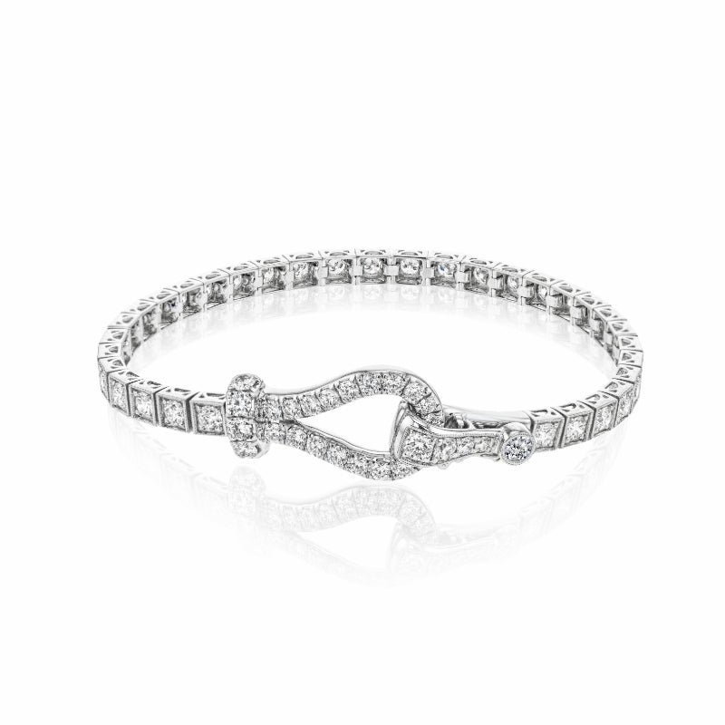 The Simon G. 18K White Gold Diamond Buckle Bracelet exudes refinement and luxury with its gleaming white gold adorned with small, square-cut white diamonds and featuring an elegant, curved buckle clasp set with additional diamonds. The bracelet is beautifully showcased against a plain white background.