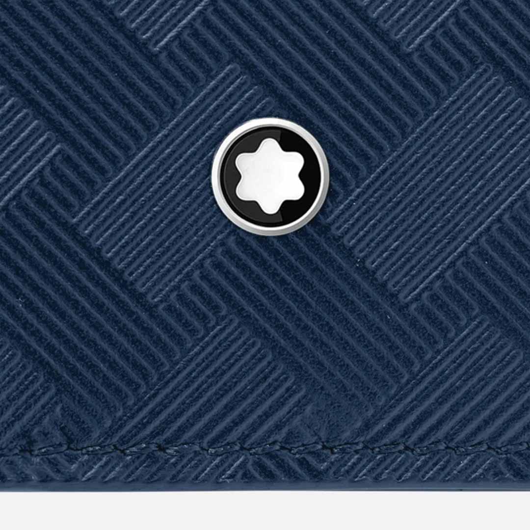 Close-up of the Montblanc Extreme 3.0 4cc Leather Blue Card Holder's textured blue leather surface, featuring a crisscross pattern. A circular metal emblem with a star shape is prominently displayed in the center, adding an elegant touch.