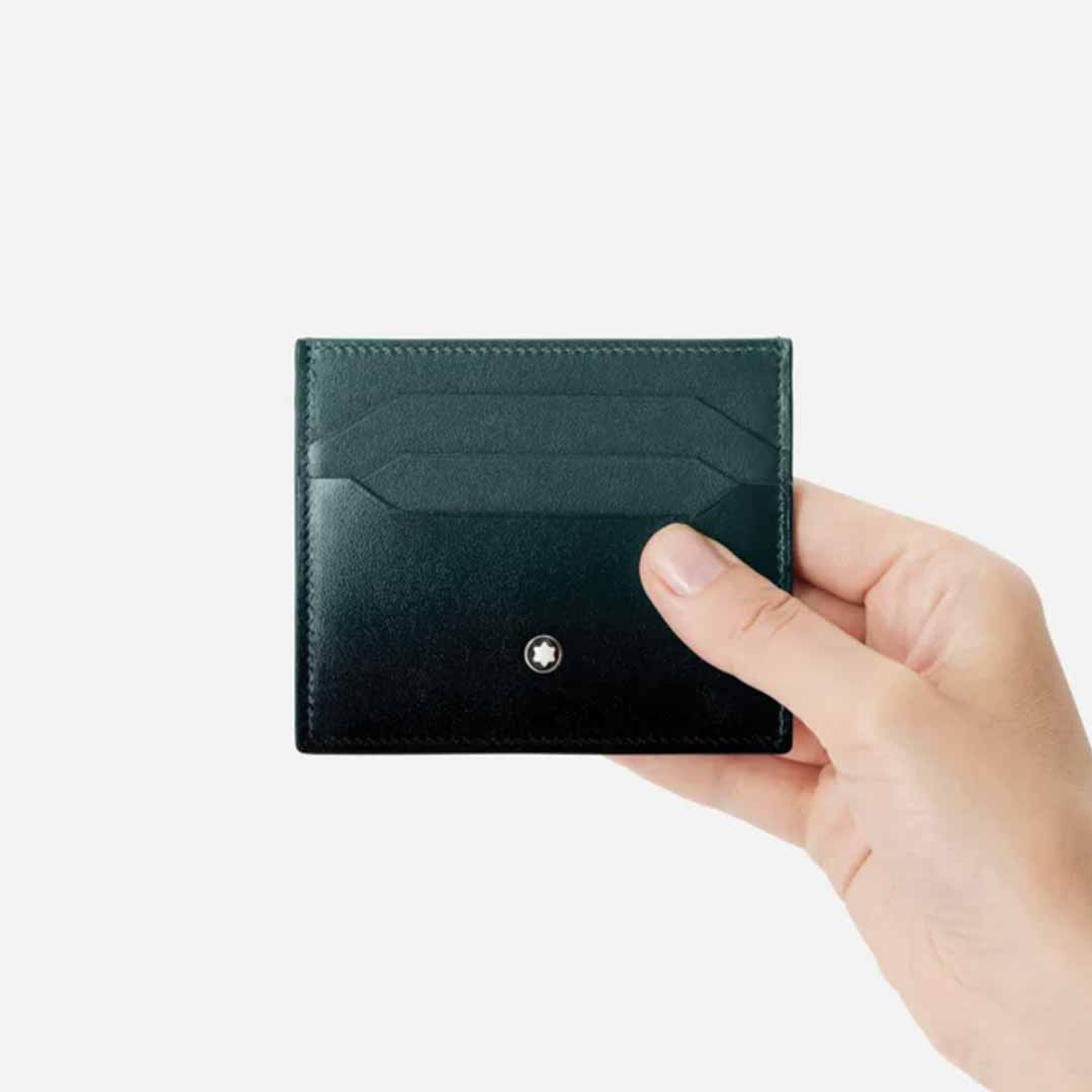 A hand holding a Montblanc Meisterstuck 6cc Leather Card Holder crafted from black leather against a plain white background, featuring a small round Montblanc logo on the front. Part of the Montblanc 100 Years Meisterstück capsule collection, it embodies timeless elegance and craftsmanship.