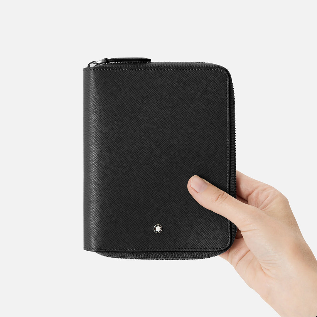 A hand holds the Montblanc 5-Pen Leather Zip Pouch in black textured Saffiano leather against a white background. A small metal Montblanc emblem adds elegance to its zippered edge design.