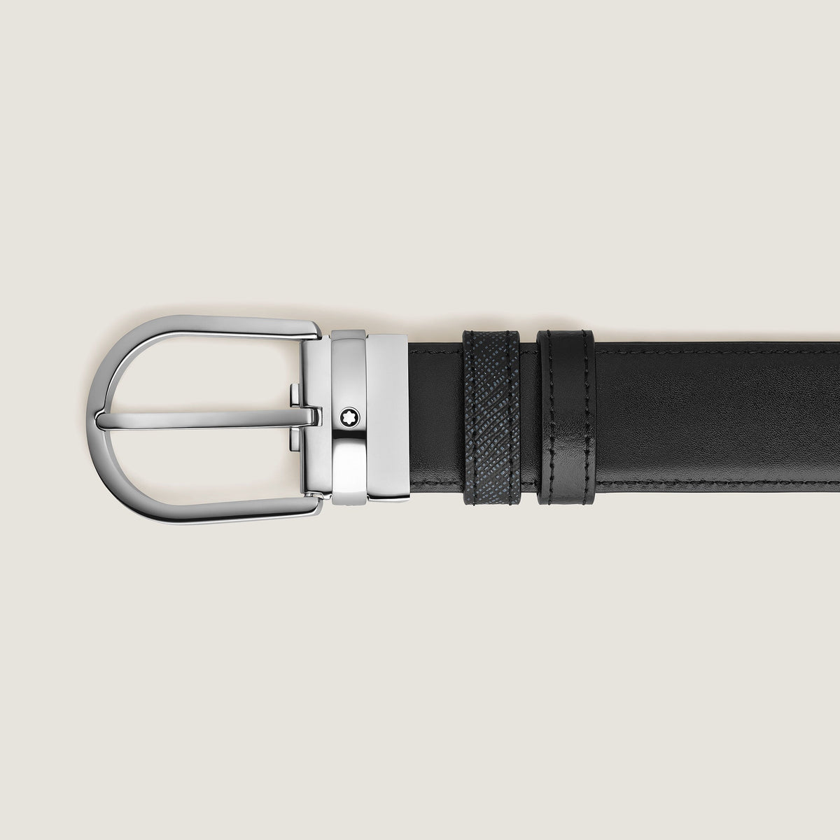 The Montblanc Horseshoe Buckle 35mm Reversible Tweed Blue and Black Leather Belt is displayed horizontally on a plain light background, featuring two loops near its silver buckle—one textured, one smooth.