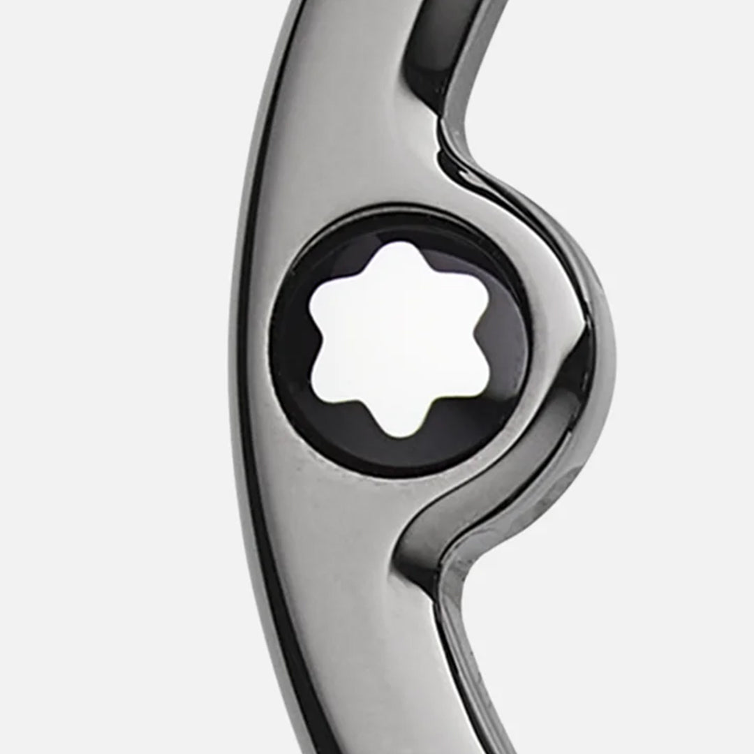 Close-up of the Montblanc Horseshoe Buckle from the Saffiano Printed Mastic 35mm Reversible Leather Belt, displaying a shiny, reflective surface with a star-shaped cutout reminiscent of the Montblanc emblem, set against a plain light gray background.