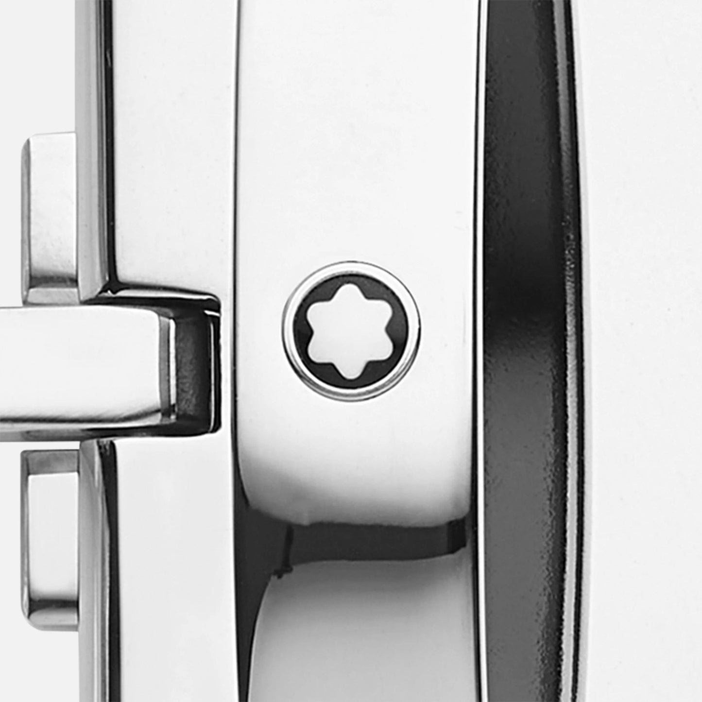 Close-up of the glossy Montblanc Horseshoe Buckle Sfumato British Green Leather Belt, with a star-shaped screw at the center of its metal surface. The sleek lines and polished finish evoke the precision of a luxury item.