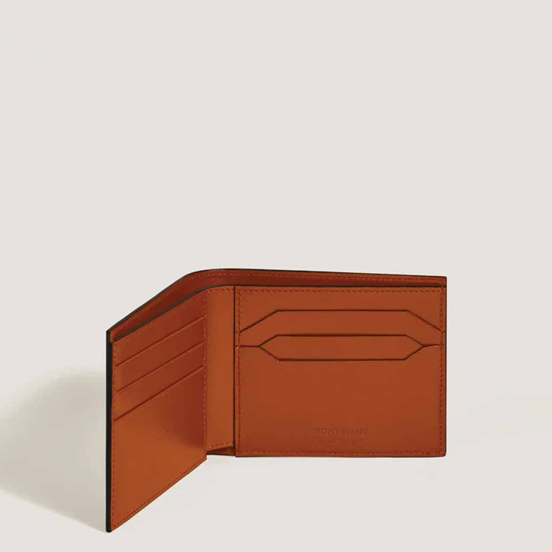 A Montblanc Meisterstück 6cc Leather Wallet in a rust hue is showcased against a light backdrop. On the left side, it includes several card slots, while the right side has an extra cardholder section that can accommodate six credit cards. The interior is characterized by its smooth texture and minimalist design.