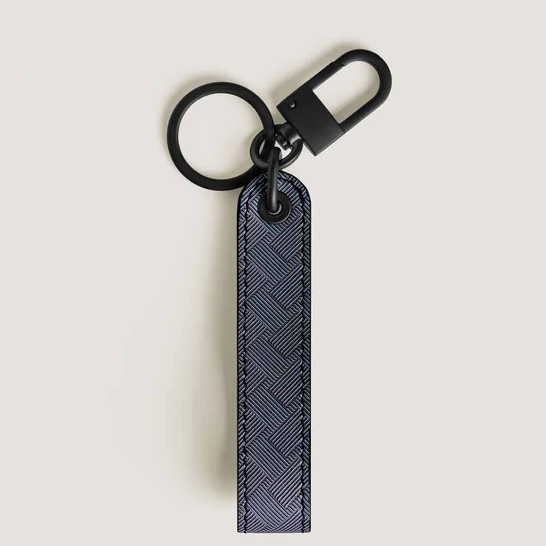 The Montblanc Extreme 3.0 Black Key FOB is a sophisticated keychain, featuring a long rectangular strap made from full-grain bovine leather with a blue textured pattern and woven design. It includes a sturdy clip at the top, making it an ideal choice for adding style to your keys.