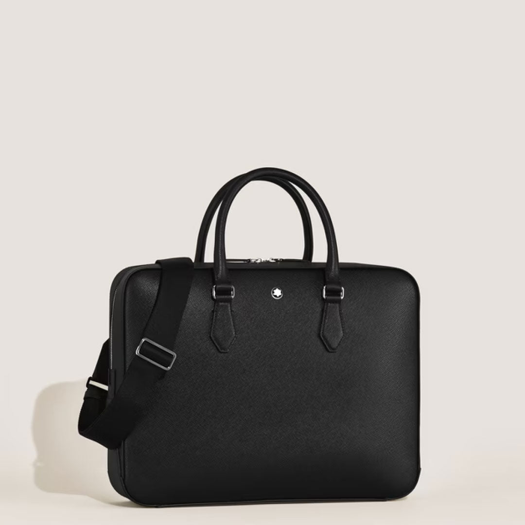 The Montblanc Sartorial Medium Leather Document Case Bag by Montblanc features black saffiano leather, two handles, a detachable shoulder strap, silver hardware, and a small circular emblem on the front against a plain light background.