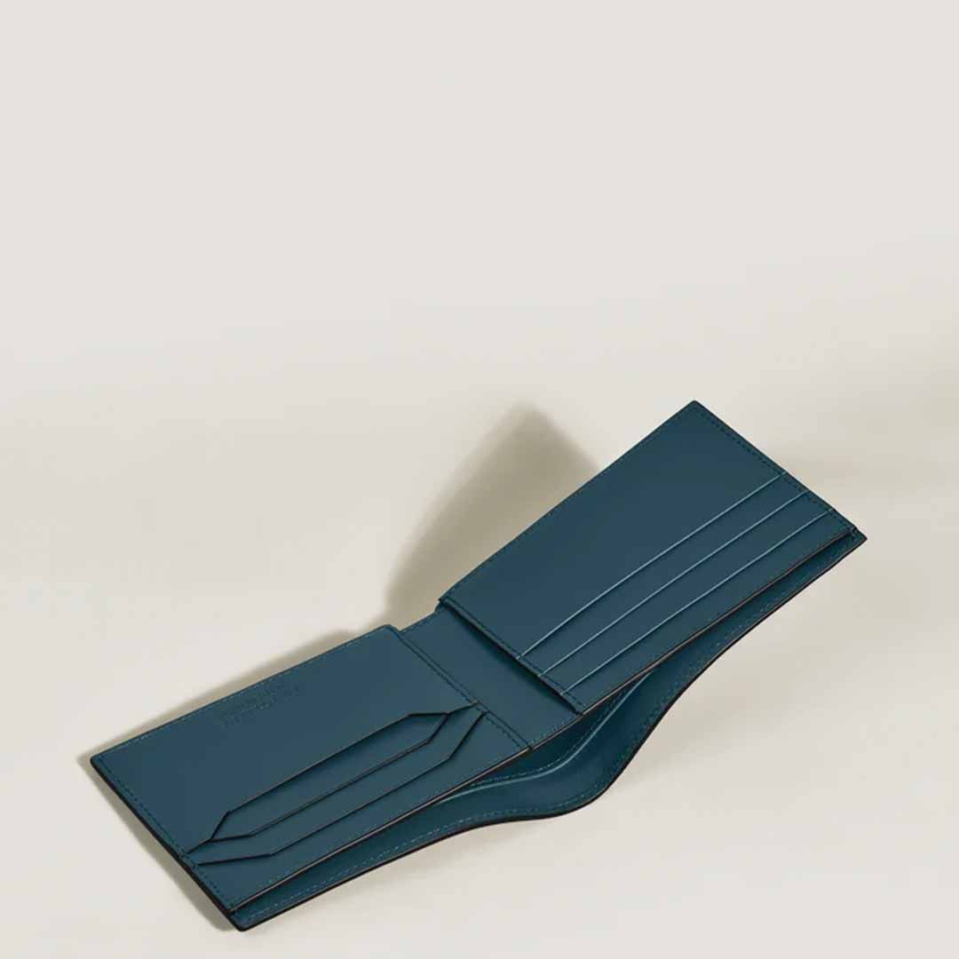 The Montblanc Extreme 3.0 6cc Leather Wallet, a stylish open dark teal wallet with several card slots and a bill compartment adorned with the Montblanc emblem, rests on a light gray surface—ideal for contemporary urban adventurers.