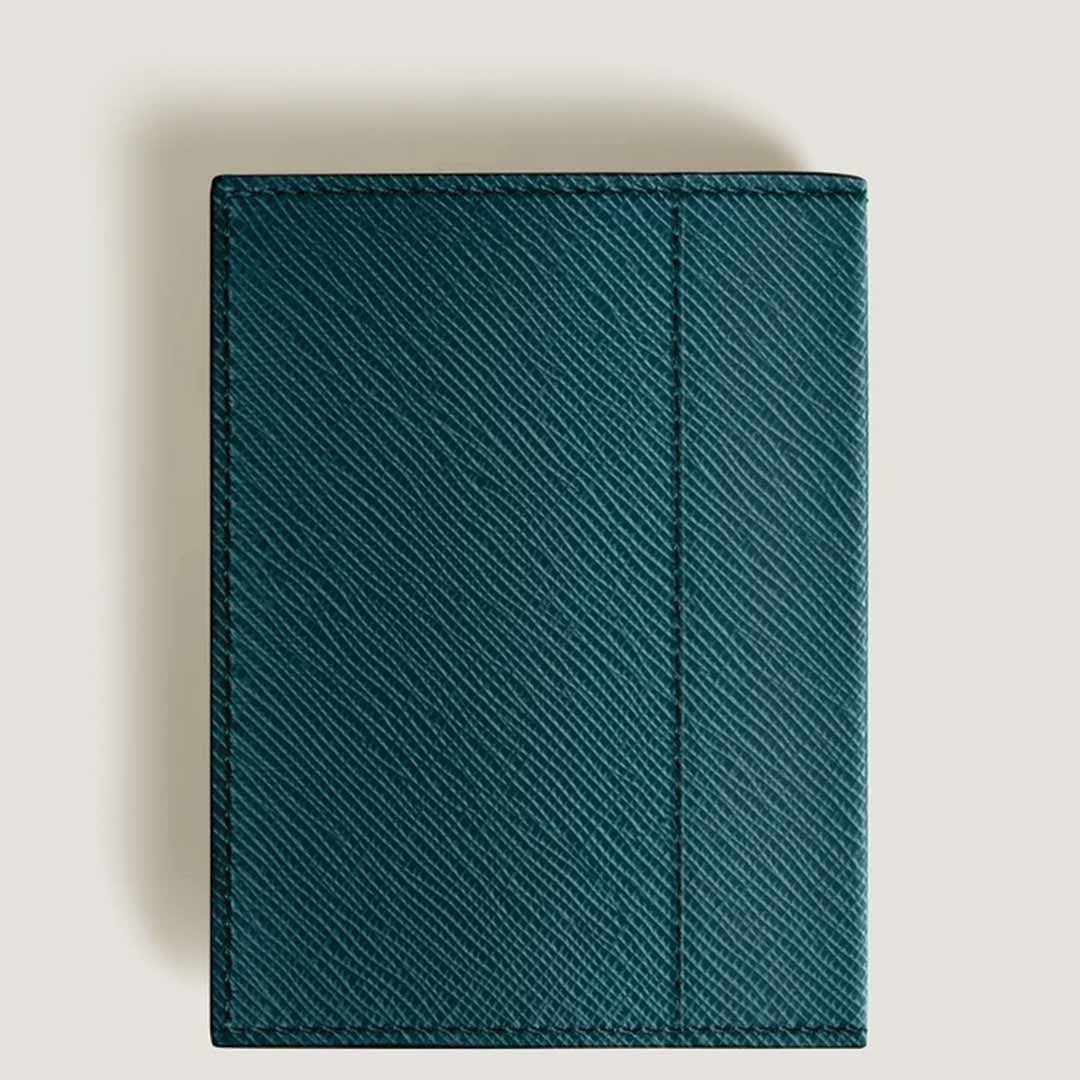 The Montblanc Sartorial 4cc Mini Leather Wallet, in a green textured finish and featuring credit card slots, sits elegantly against a light beige background, offering stylish functionality.