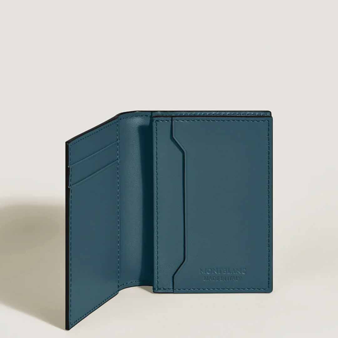 A dark teal wallet, crafted from avio blue leather, with an open, bifold design is displayed against a plain light background. On the left side, it includes two card slots, and on the right side, near the bottom, it features an embossed Montblanc Extreme 3.0 motif. This stylish accessory is known as the Montblanc Extreme 3.0 4cc Leather Card Holder by Montblanc.