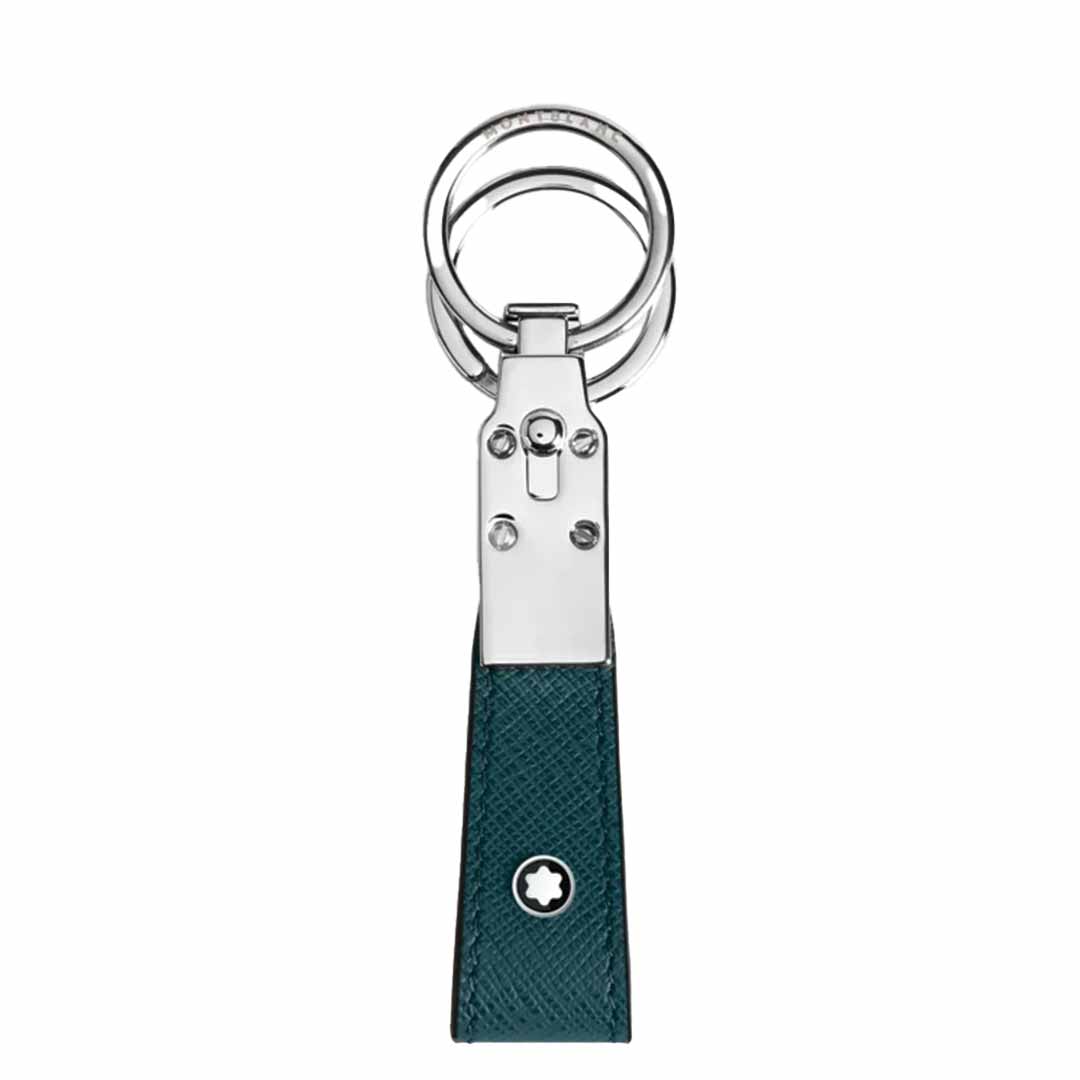 The Montblanc Sartorial Loop Key Fob showcases a stylish design with a silver metal clasp and a textured dark green, full-grain leather strap, accented by a small emblem of a white star within a circle near the bottom.